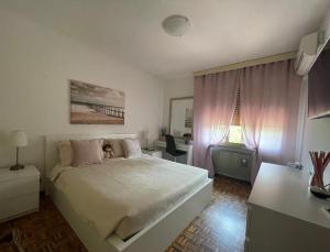 una camera con un grande letto bianco e una scrivania di B&B Da Leone a Palazzolo dello Stella