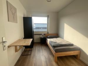 Schlafzimmer mit einem Bett, einem Tisch und einem Fenster in der Unterkunft "Live Good, Work Good" - Stadion Apartment by GG Rental Hamburg in Hamburg