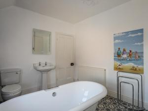 a white bathroom with a bath tub and a sink at The Old School House in Bodorgan +28 photos