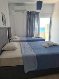 two beds in a bedroom with a window with the ocean at Lyttos in Tsoutsouros