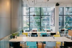 een cafetaria met tafels en stoelen en grote ramen bij Hotel Casa Amsterdam in Amsterdam