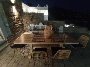 a wooden table and chairs on a patio at night at sea melody tinos 2 in Agios Sostis