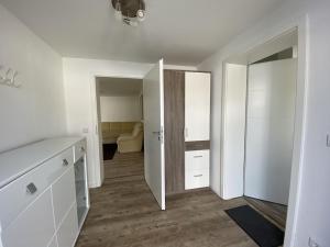 a kitchen with white cabinets and a door to a bedroom at FEWO am See Zarrendorf in Zarrendorf