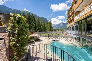 a view of a hotel with a swimming pool and mountains at Croce Bianca Leisure & Spa Hotel in Canazei