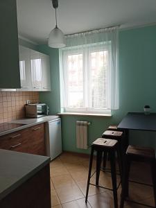cocina con paredes verdes, mesa y sillas en APARTAMENT RELAX, en Ełk