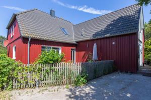een rood huis met een hek ervoor bij Kapitänshaus - Kajüte in Ahrenshoop
