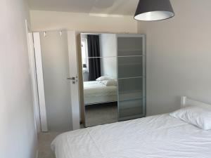 a bedroom with a white bed and a mirror at Apartament Baltic Marina in Dziwnówek