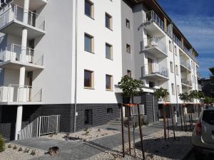 a dog sitting in front of a white building at Apartament Baltic Marina in Dziwnówek