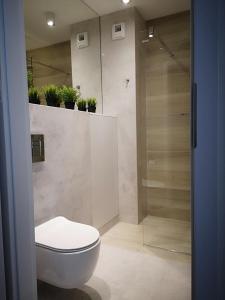 a bathroom with a toilet and a shower with plants at Apartament Baltic Marina in Dziwnówek