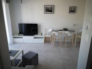 a living room with a table with chairs and a television at Apartament Baltic Marina in Dziwnówek