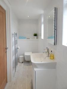La salle de bains blanche est pourvue d'un lavabo et de toilettes. dans l'établissement ChloBo Cottage near Watergate Bay, by the sea, à Newquay Bay Resort