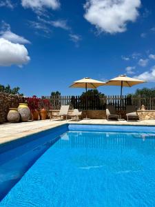 a swimming pool with two umbrellas and chairs at Can Xicu Castello in San Ferrán de ses Roques