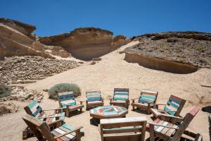 Bonito apartamento a 100 m de la playa في Arico: مجموعة كراسي وطاولات في الصحراء