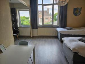 een kamer met 2 bedden, een tafel en 2 ramen bij Hotel le Bonheur in Eijsden