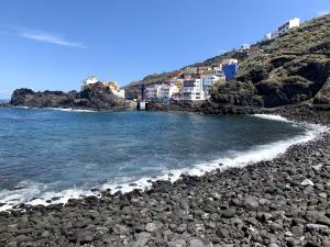 einen felsigen Strand am Meer mit Gebäuden in der Unterkunft Beachfront Apartment - Tacoronte in Santa Cruz de Tenerife