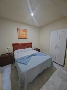 a bedroom with a bed with a blue blanket on it at Lindo piso en el corazón de Cádiz in Cádiz