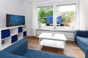 a living room with a blue couch and a white table at Ferienwohnungen Blaues Haus in Bensersiel