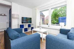 a living room with two blue chairs and a table at Ferienwohnungen Blaues Haus in Bensersiel