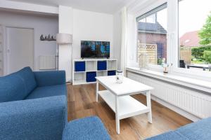 a living room with a blue couch and a white table at Ferienwohnungen Blaues Haus in Bensersiel