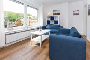 a living room with two blue chairs and a table at Ferienwohnungen Blaues Haus in Bensersiel +156 photos