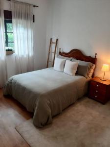a bedroom with a large bed with a wooden headboard at Retiro da Cava, piscina privada in Oleiros