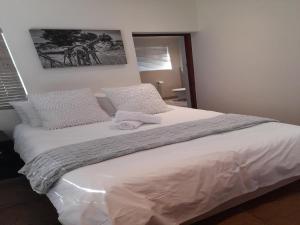 Un dormitorio con una cama grande con sábanas y almohadas blancas. en Paddabult Self Catering Cottages, en Paarl