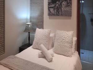 a bedroom with a bed with white pillows and a lamp at Paddabult Self Catering Cottages in Paarl