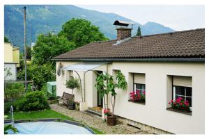 a white house with flowers on the windows of it at Ingrid's Guesthouse Gartenidylle in Spittal an der Drau