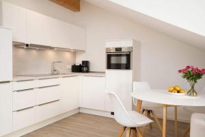 una cocina con armarios blancos y una mesa con sillas. en SEASIDE - Neubau mit Meeresblick en Sierksdorf