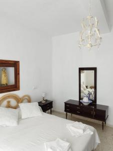 um quarto com uma cama, um espelho e um lustre em AT LA VIÑUELA em Losar de la Vera