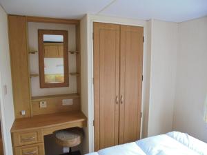 a bedroom with a bed and a dresser and a mirror at Promenade: Retreat:- 4 Berth, Access to the beach in Ingoldmells