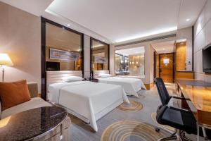 una camera d'albergo con 3 letti e una scrivania di Sheraton Zhongshan Hotel a Zhongshan