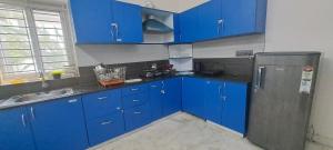 a kitchen with blue cabinets and a stainless steel refrigerator at iSTAYS - Luxe Villa, Yercaud in Yercaud