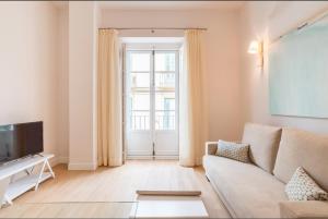 Una sala de estar con un sofá y un televisor. en Merced10 2C, en Málaga