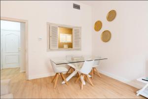 uma sala de jantar com uma mesa de vidro e cadeiras brancas em Merced10 2C em Málaga