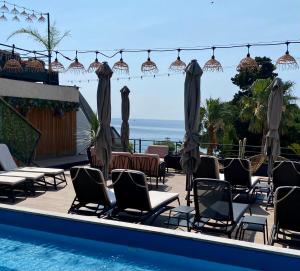 a pool with chairs and umbrellas next to a swimming pool at Les Alcyons in Le Lavandou