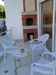 a porch with white chairs and a table and a fireplace at Апартаметы Либия Libiya в центре Кемера дуплекс две спальни, 140 кв м, 300 м до пляжа,рамещение до 5 человек in Kemer