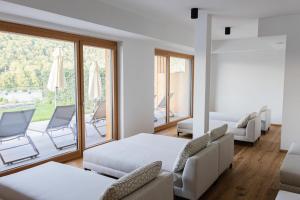 a room with two beds and chairs and a balcony at Weinhaus Nigl - Hotel, Restaurant und Spa in Senftenberg