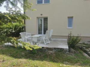 a patio with two chairs and a table in front of a house at Apartmani Romić R in Novi Travnik