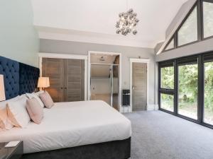 Un dormitorio con una gran cama blanca y una lámpara de araña. en Thornbury, en Great Malvern