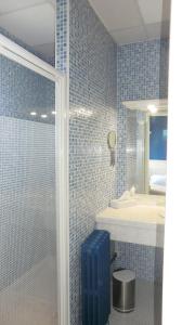 a blue tiled bathroom with a shower and a sink at Hôtel Le Boïate in Arès