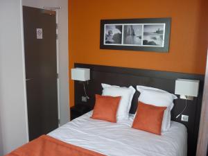 a bed with orange walls and two pillows on it at Hotel De La Plage in Quiberville