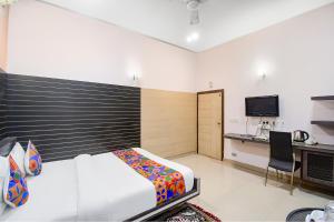 a bedroom with a bed and a desk and a television at FabExpress Gardenia in Ballygunge