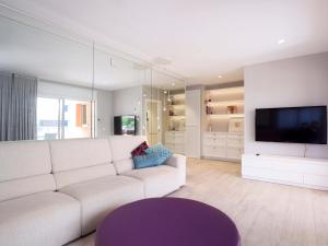 ein Wohnzimmer mit einem weißen Sofa und einem TV in der Unterkunft Sagaro Mar D32011 in Sant Feliu de Guixols
