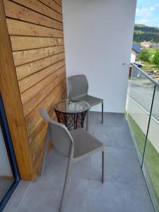 um pátio com 2 cadeiras e uma mesa na varanda em Apartmány VLK em Zuberec