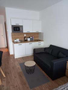 ein Wohnzimmer mit einem schwarzen Sofa und einer Küche in der Unterkunft Apartmány VLK in Zuberec