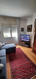a living room with a blue couch and a red rug at Chez Jeanne in Carentan