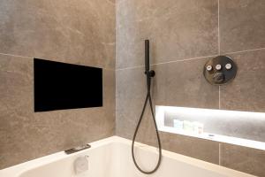 ein Bad mit einer Badewanne und einem TV an der Wand in der Unterkunft Luxury spacious modern new apartment -fully equipped in London