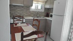 a kitchen with a table and chairs and a refrigerator at Askeli Breeze in Poros