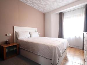 1 dormitorio con cama blanca y ventana en E22164 Sant Ramon en Sant Feliu de Guixols